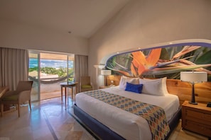 Habitación de hotel con una cama grande, una silla, una mesita y vistas al exterior.