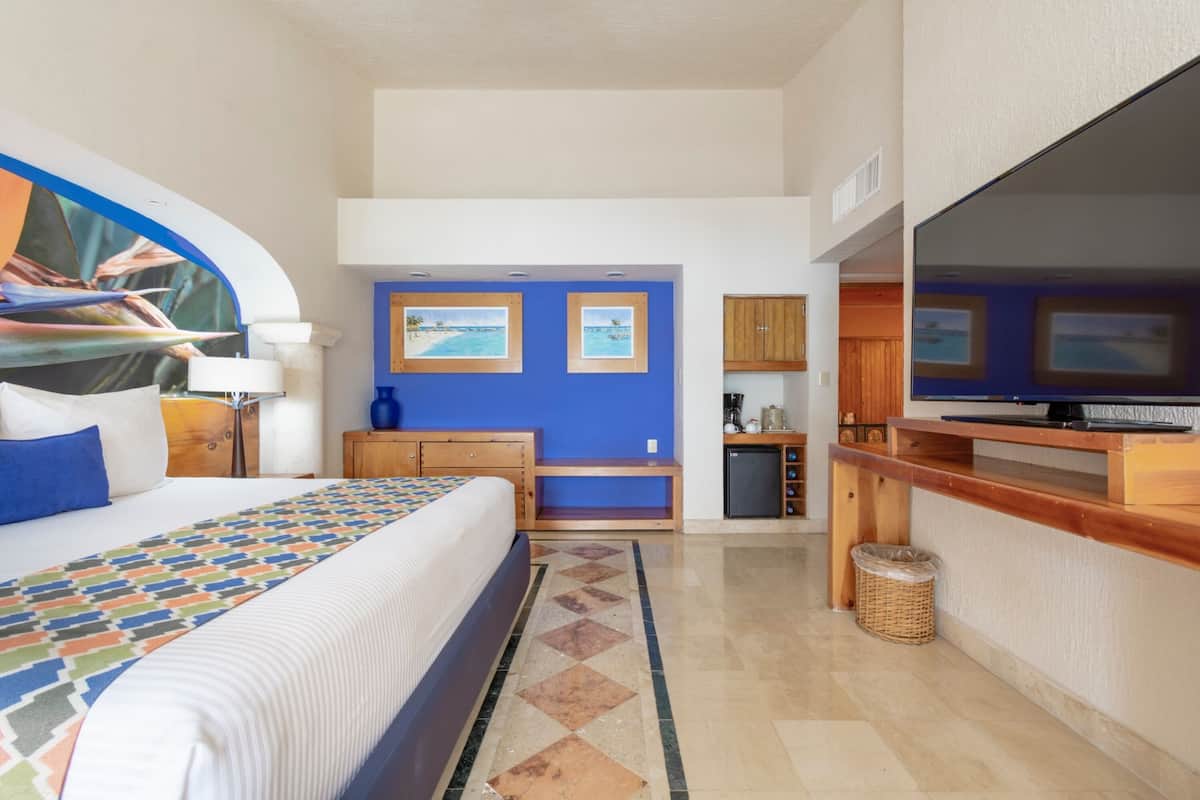 Une chambre d’hôtel avec un grand lit, une télévision, une petite kitchenette et une salle de bain.