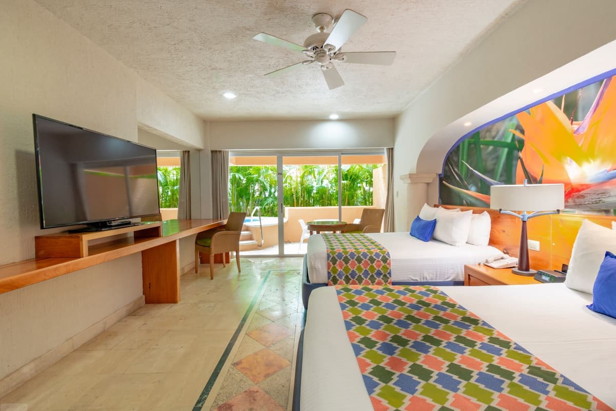 Une chambre d’hôtel avec un lit, un bureau avec une télévision, une chaise, une table et une vue sur la verdure.