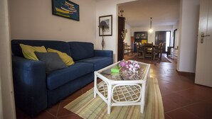 A living room with a blue sofa, a white coffee table, and a dining area in the background. - Amazing House in Evora (Évora)