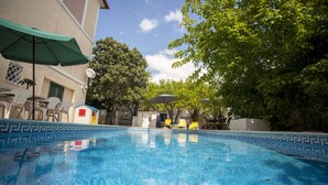 A swimming pool with a tiled edge, surrounded by outdoor furniture and trees. - Amazing House in Evora (Évora)