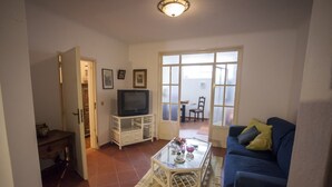 A living room with a TV, a blue sofa, and a glass coffee table. - Amazing House in Evora (Évora)