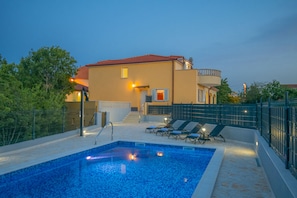 Une piscine avec des chaises longues et un escalier menant à un balcon.