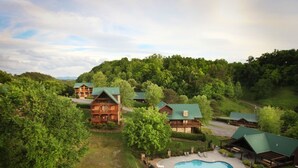 Eine Lodge mit mehreren Ferienhäusern, einem Schwimmbad und einer üppigen, grünen Landschaft.