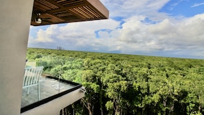 Ein Balkon mit Blick auf einen dichten Wald und eine Stromleitung in der Ferne.