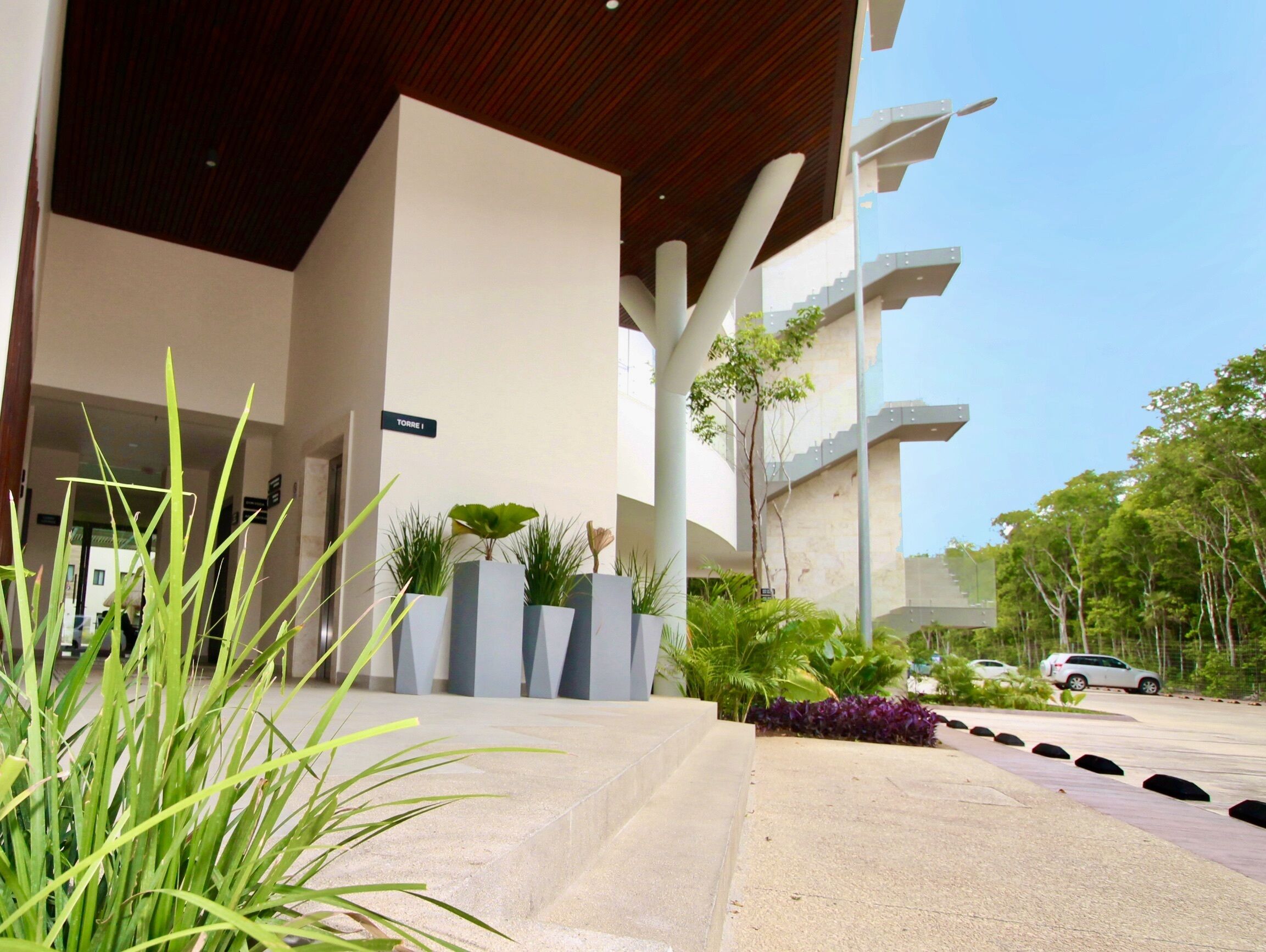 Un bâtiment moderne doté d’un toit plat, de grandes colonnes et d’une enseigne indiquant « TORRE I ».