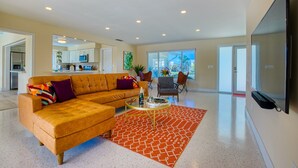 A spacious living room with a sectional sofa, a coffee table, and a large window offering a view of the outdoors.