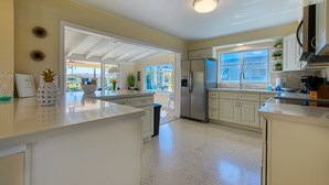 A modern kitchen with white cabinetry, stainless steel appliances, and a large window providing natural light.