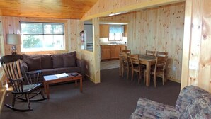 A cozy cabin interior with a living room, dining area, and kitchen. - Cottage #22 - 3 bedroom/1 bath (Cape Vincent)