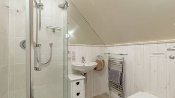 A bathroom with a glass shower enclosure, a sink, and a toilet.