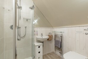 Un baño con ducha de vidrio, lavamanos blanco y barra para toallas.