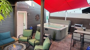 A patio area with a hot tub, seating, and a barbecue grill.