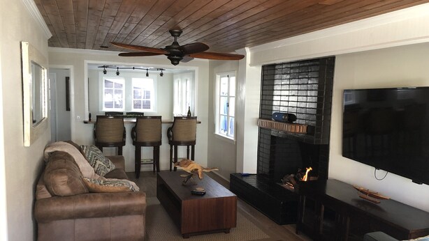 A living room with a fireplace, a television, and a ceiling fan.