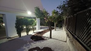 En sti med dekorative stenmønstre, et træ og en bygning med hvid facade.