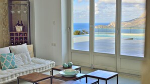 Ein Wohnzimmer mit weißem Sofa, Couchtisch und Meerblick durch große Fenster.