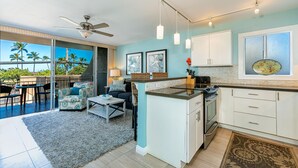 Una cocina moderna con una isla central, armarios blancos y vistas al exterior.