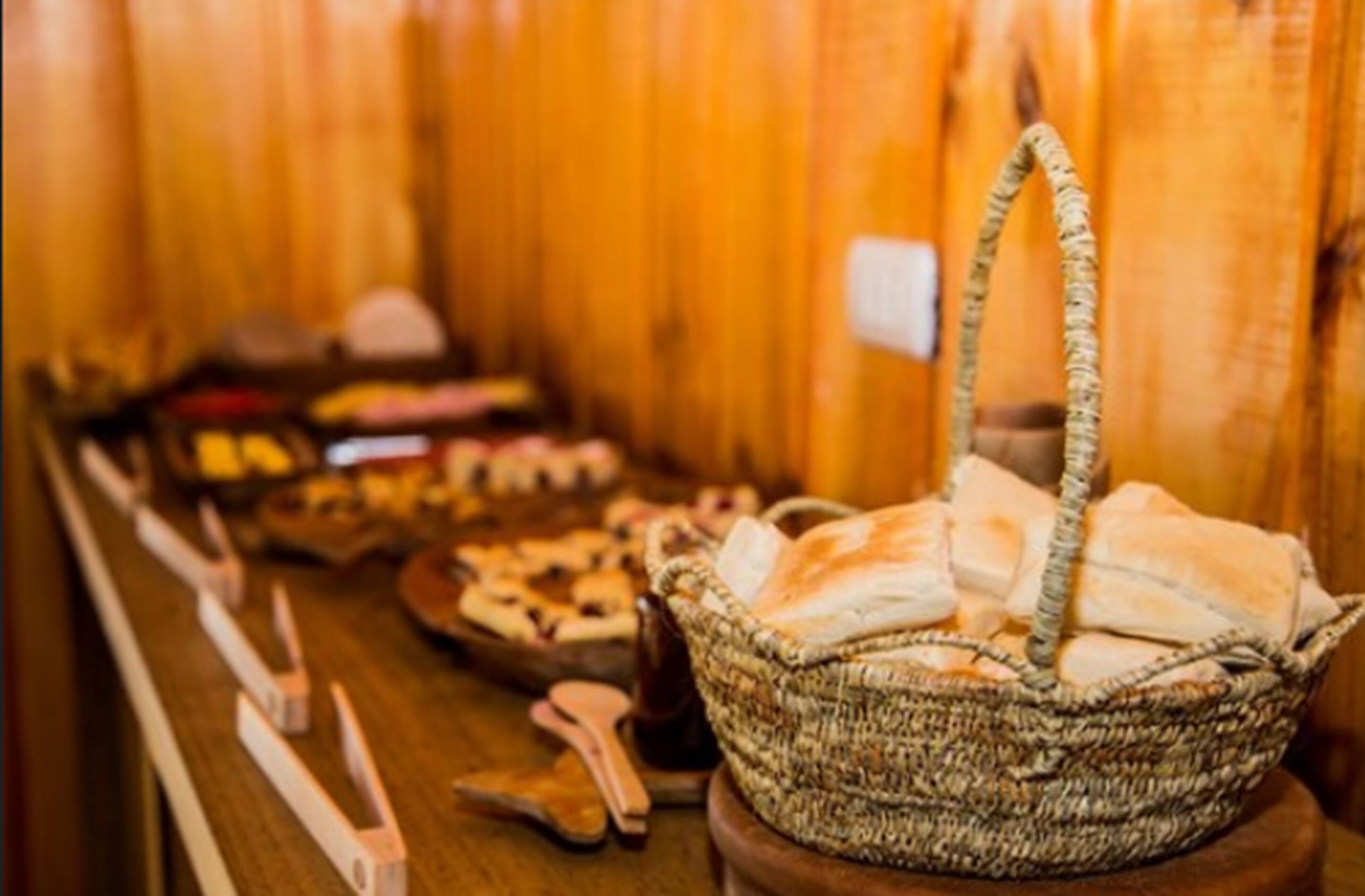 A buffet table with various food items and a woven basket with bread.