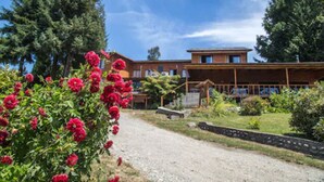 A building with a gravel driveway, surrounded by greenery and trees. - Puchaley Lafquen (Panguipulli)
