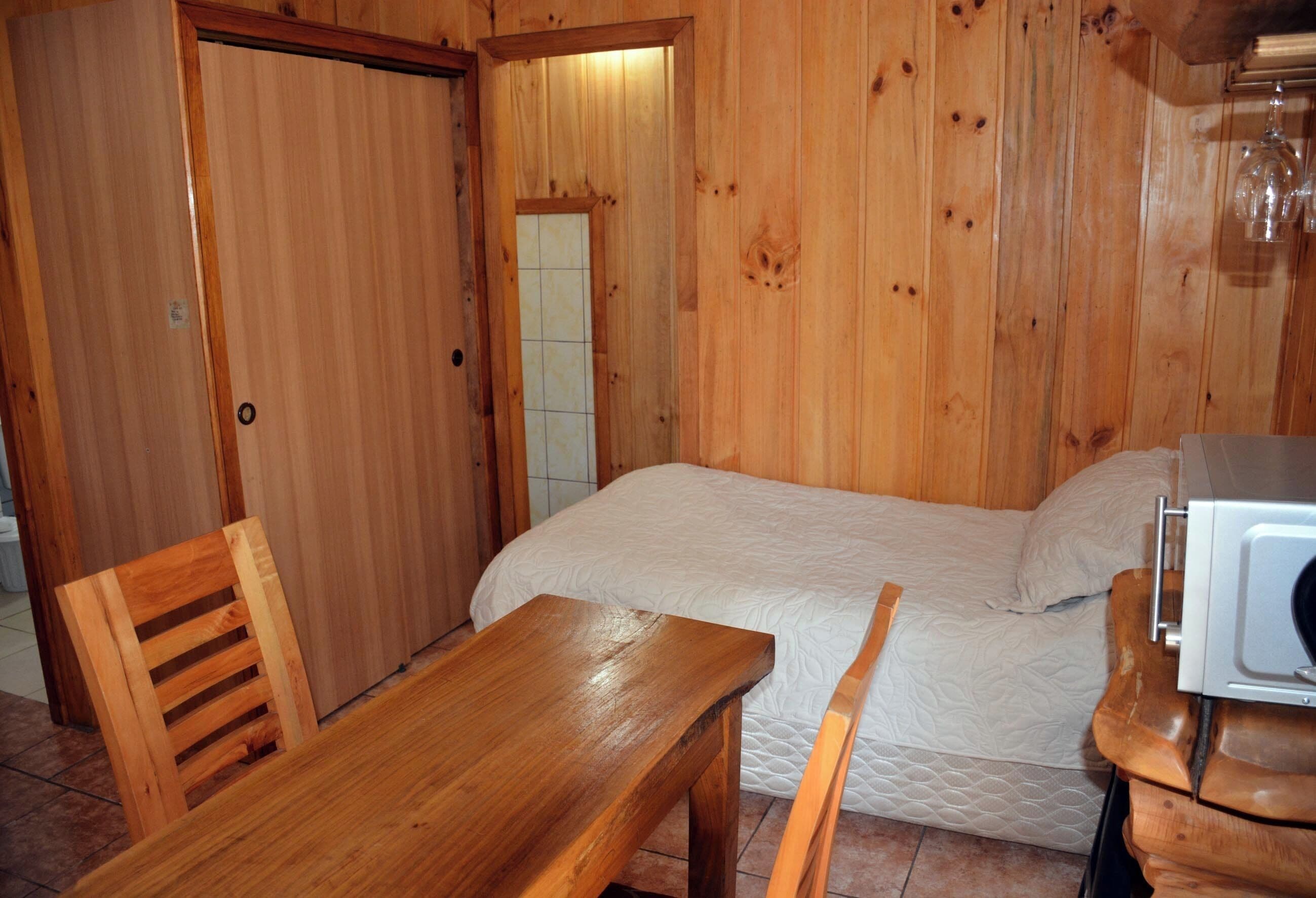 Una habitación de madera con una cama, una mesa y una silla.