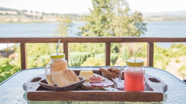 A table with a tray of food and drinks, overlooking a lake. - Puchaley Lafquen (Panguipulli)