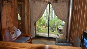 A wooden room with a bed, a fireplace, and a view of the outdoors. - Puchaley Lafquen (Panguipulli)