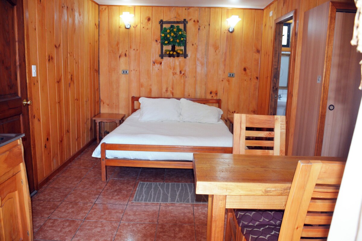 Una habitación con paneles de madera, una cama, una mesa y una silla.