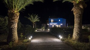 A pathway leading to a house at night, surrounded by palm trees and lit by pathway lights. - 100mt to the Beach ★ Stunning Sunset ★ Private pool ★ Exclusive location (Kokkino Chorio)