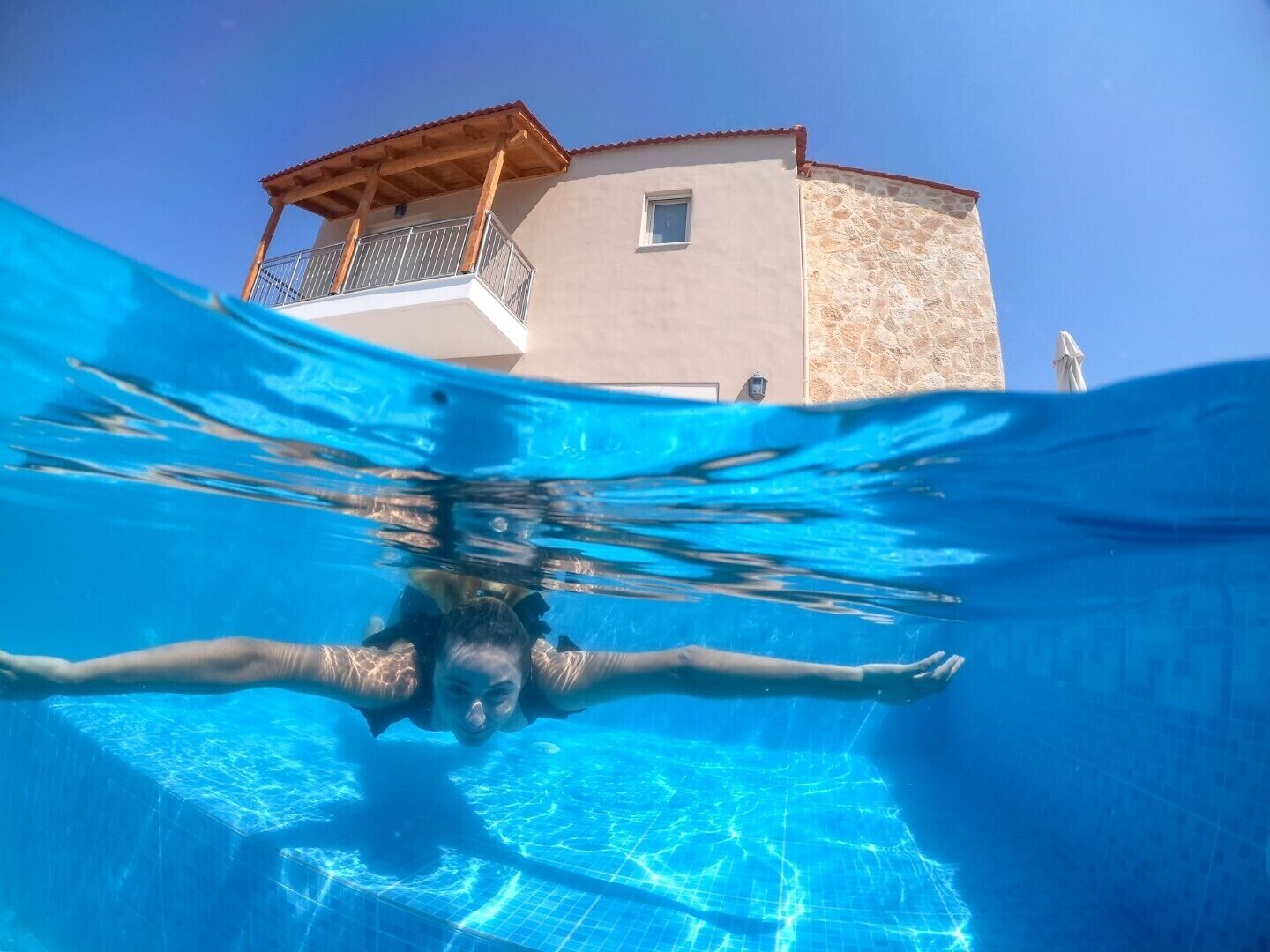 A person swimming in a pool with a building in the background.