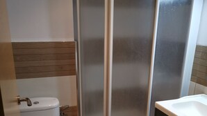 Un baño con inodoro, cabina de ducha y lavamanos.