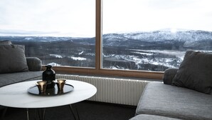 A modern living room with a large window offering a snowy mountain view. - Hemavans Högfjällshotell (Hemavan)