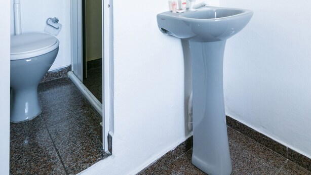 A bathroom with a toilet, a pedestal sink, and a mirror. - OYO Hotel da Praia (Tramandai)