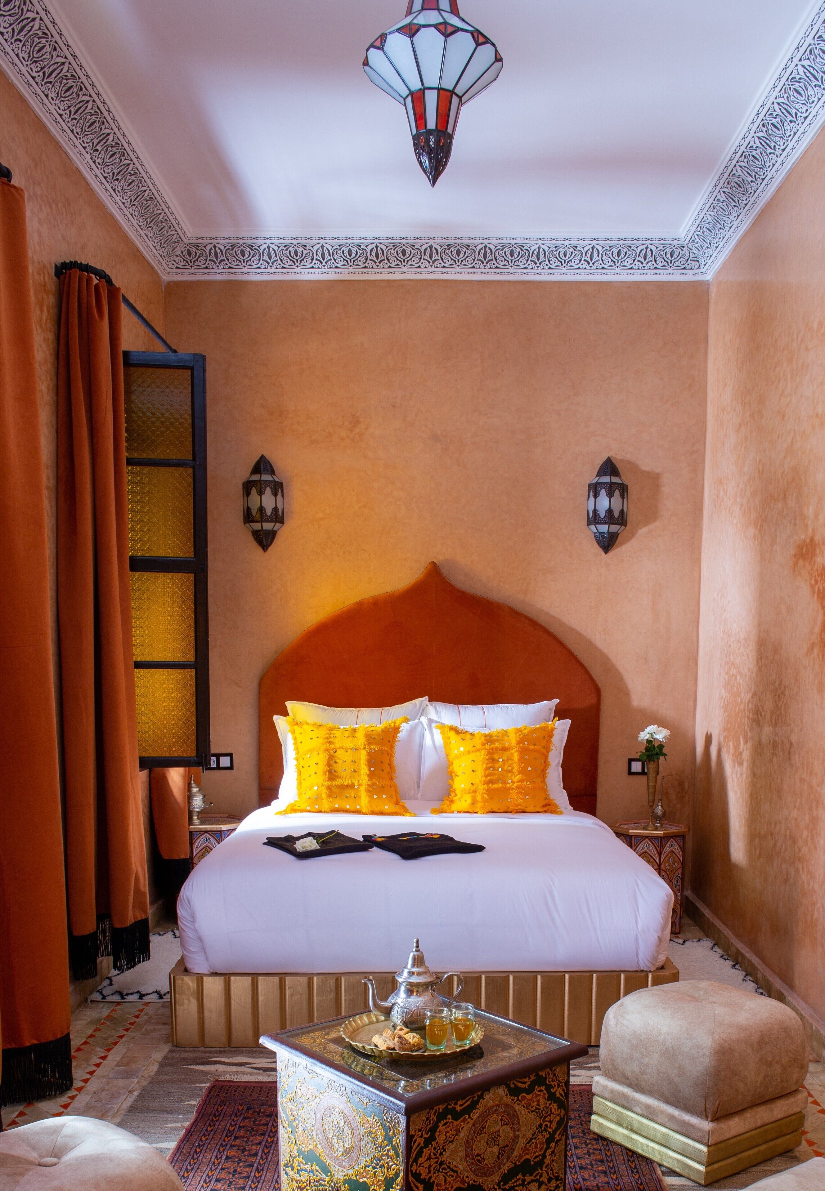 A bedroom with a large bed, a nightstand, a decorative table, and a hanging light fixture.