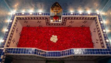 Una bañera con pétalos de rosa roja y un objeto dorado en el techo.