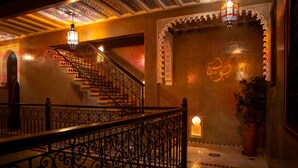 A staircase with ornate railings and a patterned floor, leading to a room with a decorative wall and a potted plant. - Riad Touda (Marrakech)