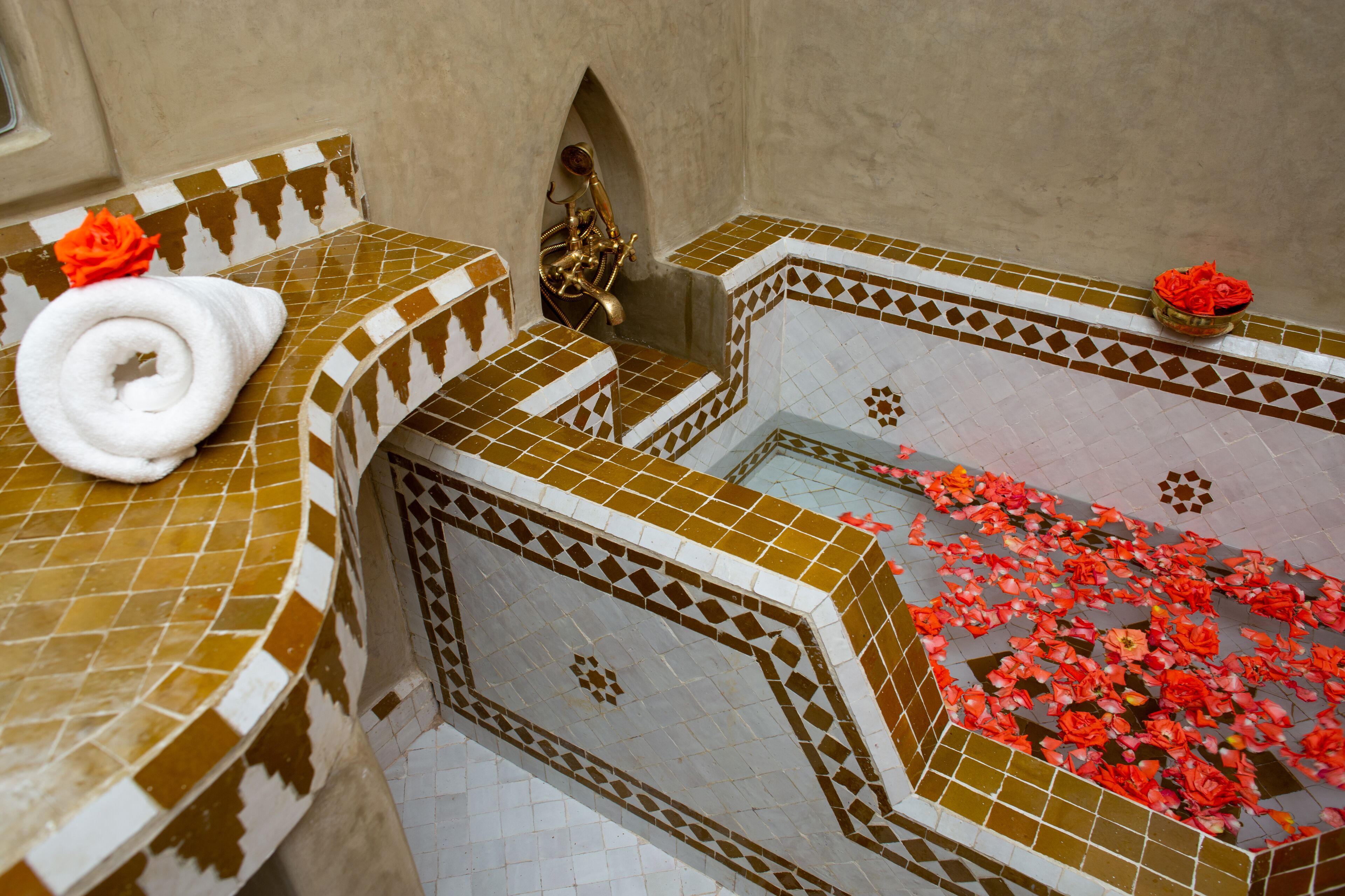 A bathroom with a mosaic tile design, a towel, and a flower.