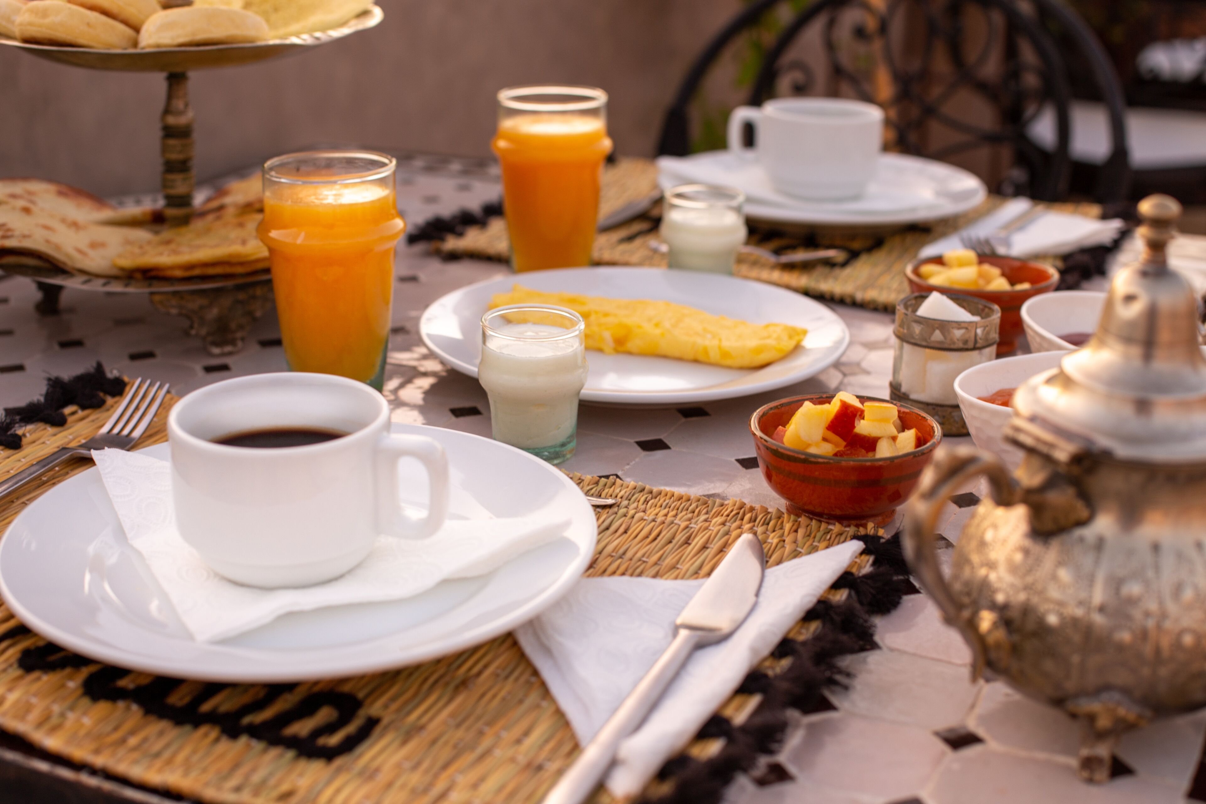 A breakfast setting with a variety of food and drinks, including a plate of eggs, a glass of orange juice, and a cup of coffee.
