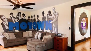 A living room with a sectional sofa, a wooden floor, a ceiling fan, and a wall with a large 'MOTOWN' poster. - Motown BNB . Experience Detroit in style. (Detroit)