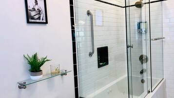 Een bad/douchecombinatie, een bubbelbad, een haardroger, handdoeken