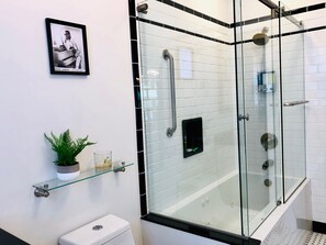 Een bad/douchecombinatie, een bubbelbad, een haardroger, handdoeken