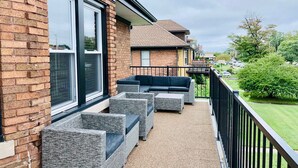 A balcony with wicker furniture, a brick wall, and a view of neighboring houses. - Motown BNB . Experience Detroit in style. (Detroit)