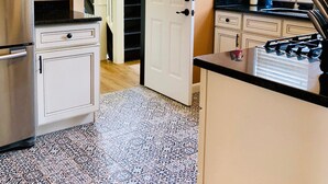 A compact kitchen with a refrigerator, stove, and cabinets. A door leads to a staircase. - Motown BNB . Experience Detroit in style. (Detroit)