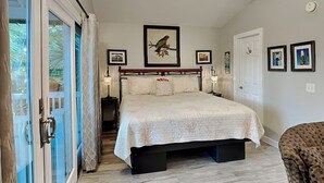 A bedroom with a large bed, a ceiling fan, and a view through a glass door.