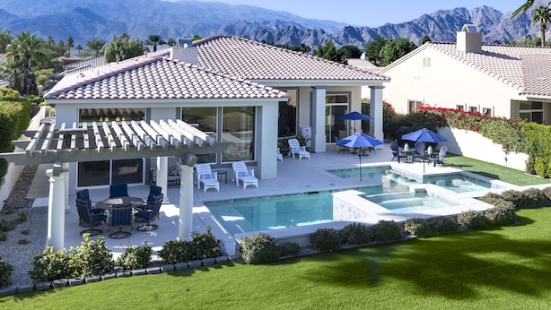 Ein Haus mit Swimmingpool, Terrassenmöbeln und Bergblick.