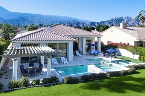 Une maison avec une piscine, du mobilier de jardin et une vue sur les montagnes.