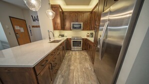 Eine moderne Küche mit Holzschränken, Edelstahlgeräten und einer großen Kochinsel.