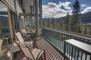 A balcony with a table and chairs, overlooking a mountainous landscape with trees and a lake. - Saints John 2526 (Keystone)