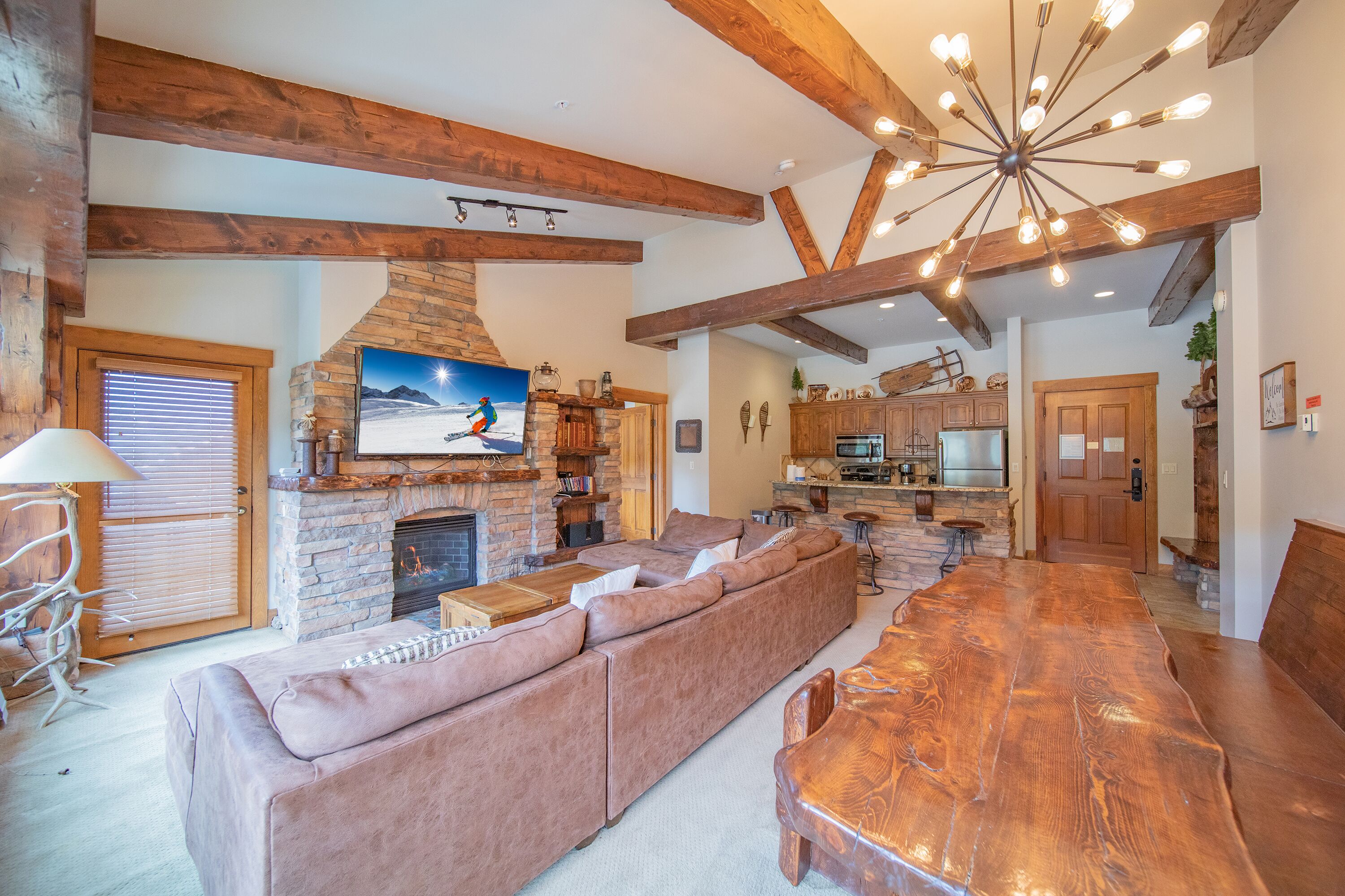 A spacious living area with a large wooden dining table, a stone fireplace, and a cozy seating arrangement.