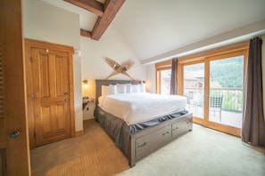 A bedroom with a large bed, wooden wardrobe, and a balcony with a view of a mountain. - Springs 8911 (Keystone)