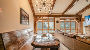 A rustic interior with a wooden bench, a stone fireplace, and a large window with a view of the outdoors. - Springs 8911 (Keystone)