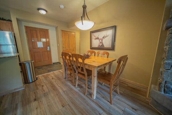Un coin repas avec une table et des chaises en bois, un luminaire suspendu et un tableau encadré au mur.